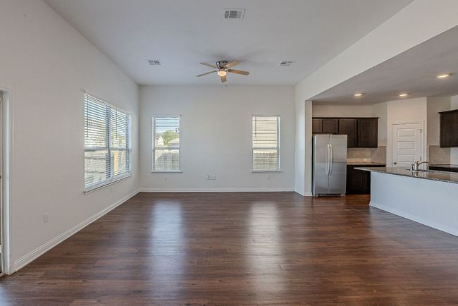 Unfurnished living room with baseboards, dark wood-style floors, visible vents, and a ceiling fan | Image 8