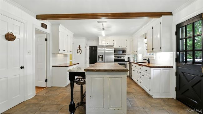 Kitchen featuring stainless steel appliances, beamed ceiling, dark stone finish flooring, tasteful backsplash, and white cabinetry | Image 47