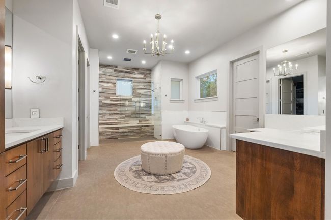 Primary Bathroom featuring visible vents, two vanities, tiled shower, and an inviting chandelier | Image 16