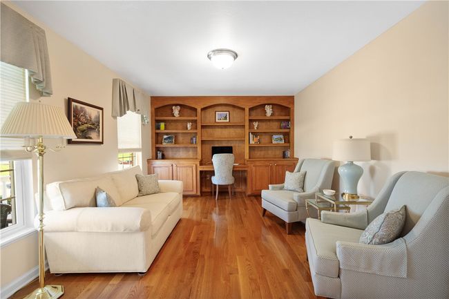 Hardwood flooring and built-in bookcases enhance the main level den. | Image 4