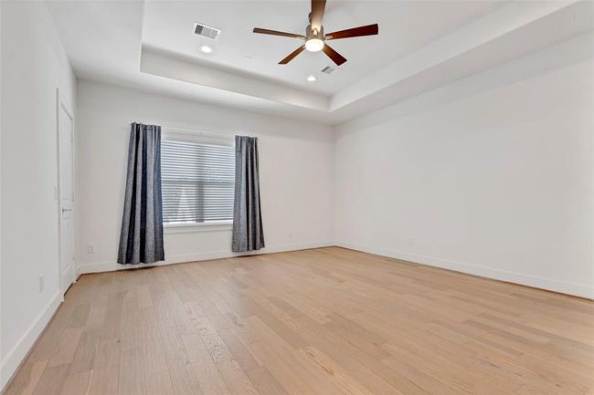 The main bedroom is spacious, featuring wooded floor, plenty natural lights & a ceiling fan. | Image 16