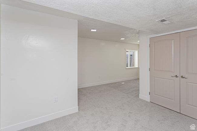 Spare room featuring a textured ceiling, visible vents, baseboards, and light carpet | Image 31