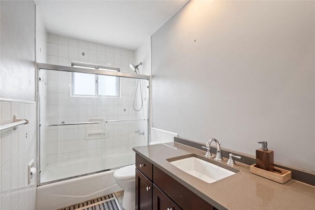 Bedroom featuring access to exterior, a baseboard radiator, vaulted ceiling, and wood finished floors | Image 21