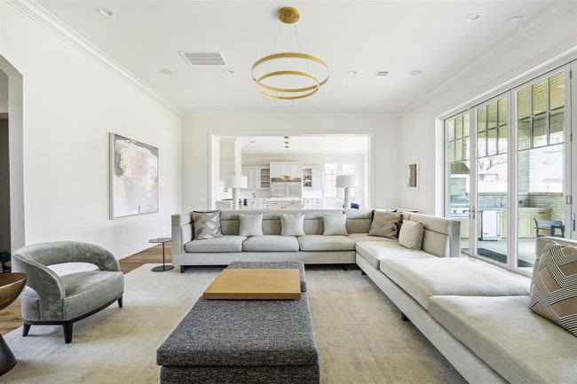 Reentering the family room, we see how well-designed the space is for seamless indoor-outdoor living with an open-concept layout and floor-to-ceiling sliding glass doors that extend to the outdoor living area. A striking chandelier, gleaming oak hardwood floors, and soaring 12-foot ceilings enhance the room’s elegance and airy ambiance. | Image 10