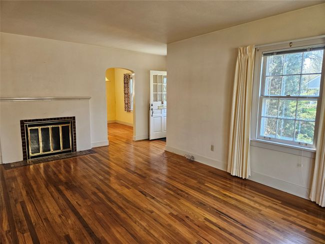 Unfurnished living room featuring plenty of natural light, hardwood / wood-style flooring, baseboards, and arched walkways | Image 7