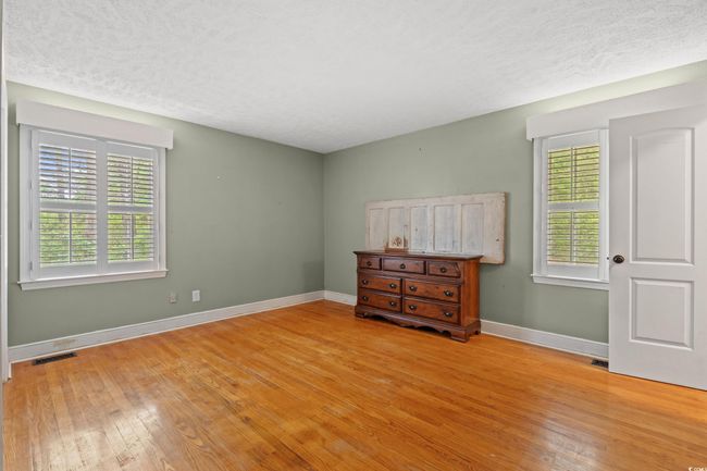 Bedroom with light wood-type flooring, a textured ceiling, baseboards, and multiple windows | Image 9