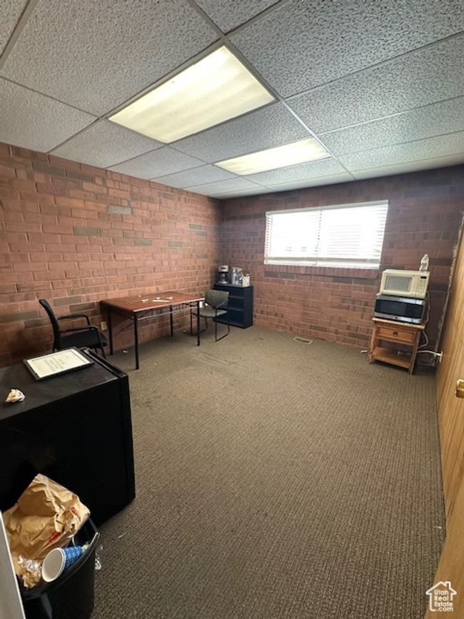 Interior space featuring a paneled ceiling and brick wall | Image 12