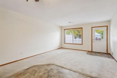 The front door opens into a spacious living area bathed in natural light, thanks to a large window that frames a serene view of your porch. | Image 3