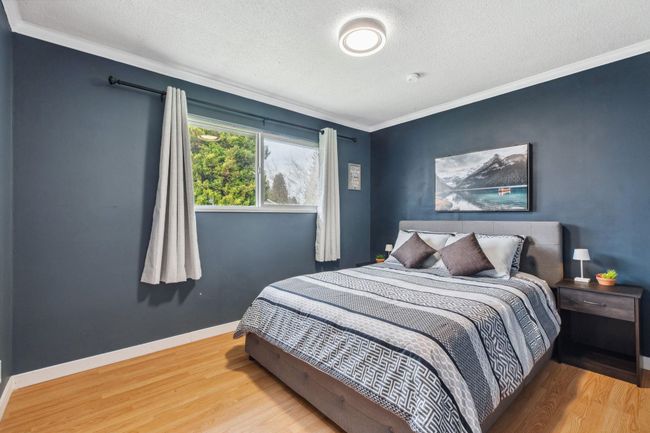Bedroom with a textured ceiling, crown molding, and wood finished floors | Image 22