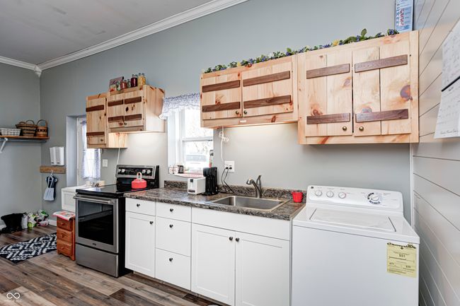 kitchen featuring ornamental molding, open shelves, washer / dryer, stainless steel range with electric cooktop, and a sink | Image 52