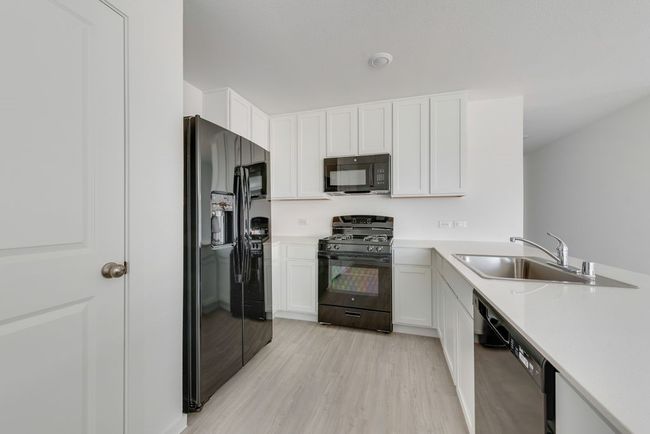 Kitchen featuring black appliances, light countertops, light wood-style floors, and white cabinetry | Image 11