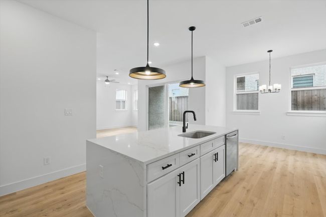 Kitchen featuring a sink, dishwasher, light wood finished floors, baseboards, and a chandelier | Image 16