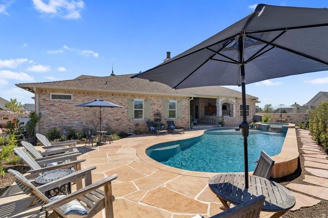 The pool features a sun ledge and two pool "shelves" with a raised back wall, all with Pebble Sheen plaster and a spillover feature and bubbles. | Image 39
