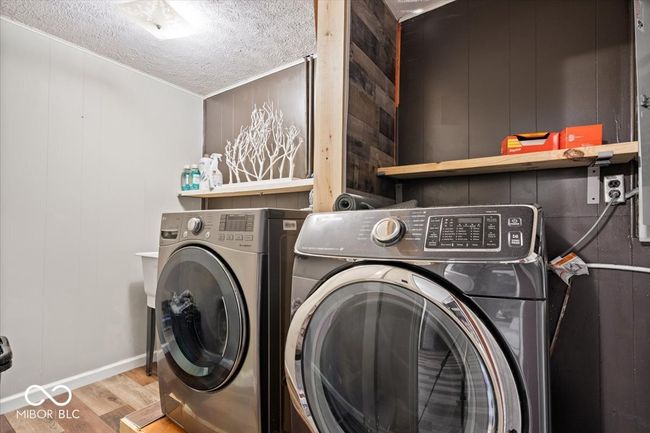 clothes washing area featuring washer and dryer, a textured ceiling, and wood finished floors | Image 33