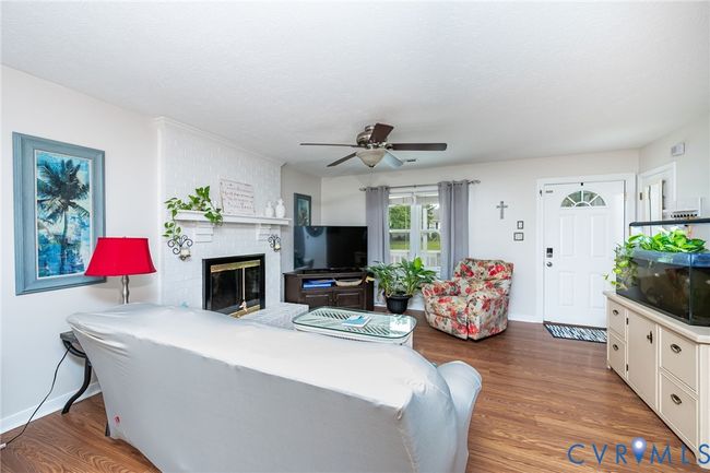 Living room with a brick fireplace, wood finished floors, ceiling fan, and a textured ceiling | Image 6