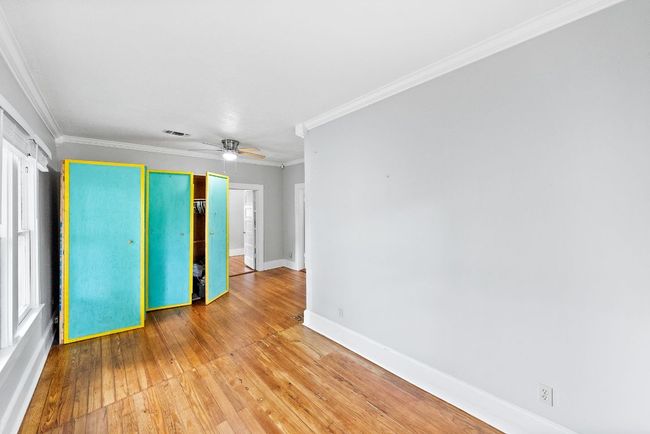Unfurnished bedroom with wood-type flooring, baseboards, crown molding, a closet, and ceiling fan | Image 13