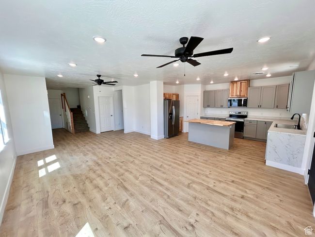 Kitchen featuring recessed lighting, a sink, stainless steel appliances, a center island, and open floor plan | Image 5