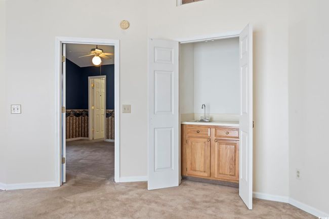 Corridor with light colored carpet, a sink, and baseboards | Image 12
