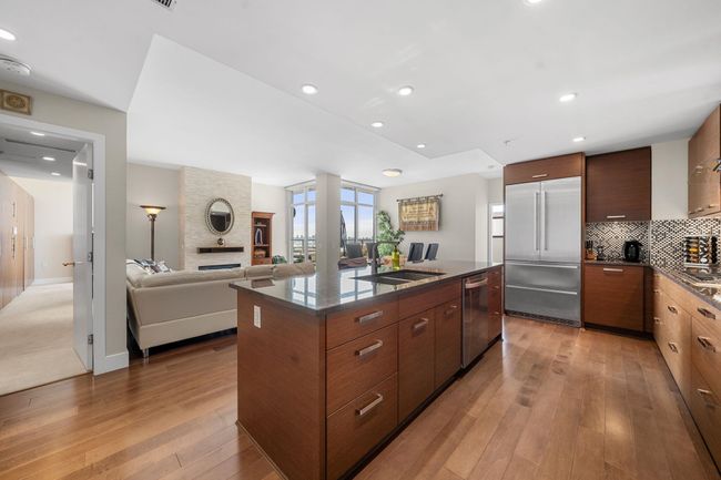 Kitchen featuring stainless steel appliances, modern cabinets, light wood-style floors, tasteful backsplash, and a kitchen island with sink | Image 4