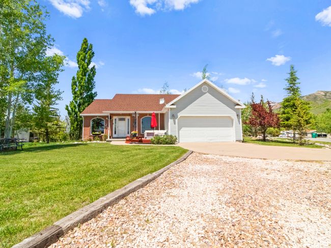 Ranch-style house featuring an attached garage, a front lawn, driveway, and covered porch | Image 27
