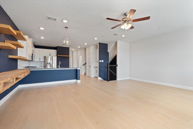 Kitchen with light wood-type flooring, appliances with stainless steel finishes, hanging light fixtures, and white cabinetry | Image 17