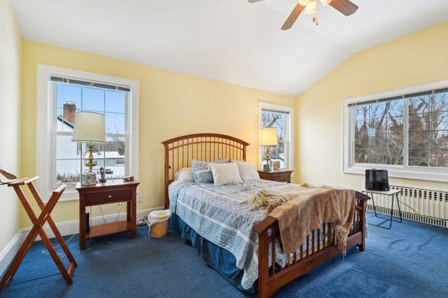 Bedroom with ceiling fan, radiator heating unit, vaulted ceiling, and dark colored carpet | Image 19