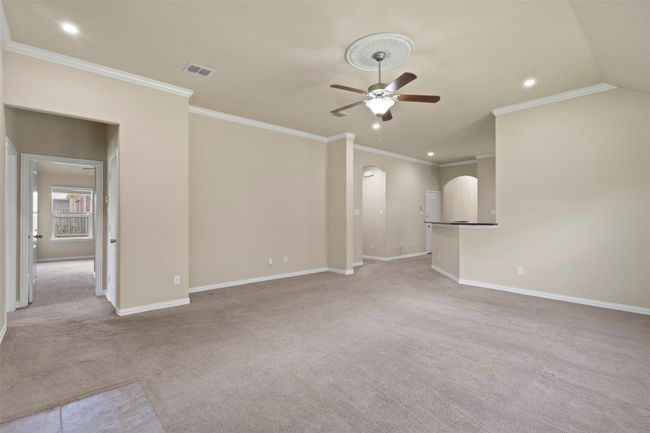 Unfurnished living room with a ceiling fan, light carpet, arched walkways, recessed lighting, and ornamental molding | Image 14