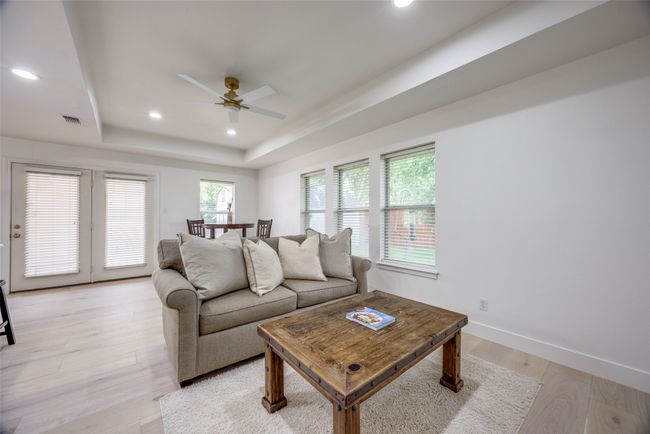 Living area with ceiling fan, a raised ceiling, light wood finished floors, and recessed lighting | Image 15