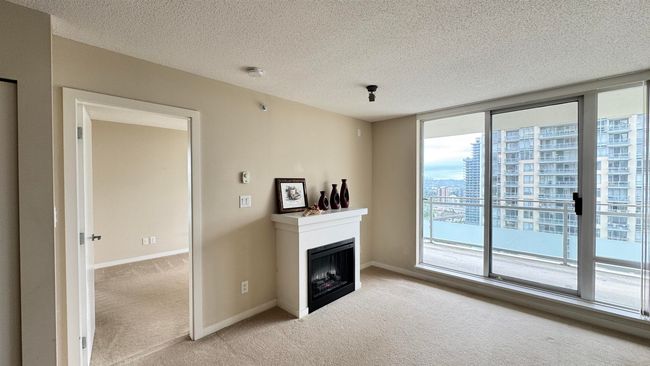 Unfurnished living room with light colored carpet, a fireplace, a textured ceiling, and baseboards | Image 11