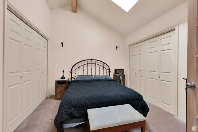 Carpeted bedroom with high vaulted ceiling, a closet, a skylight, and beamed ceiling | Image 15