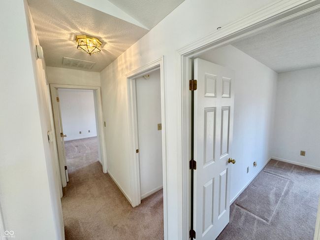 hall with light colored carpet, baseboards, and a textured ceiling | Image 7