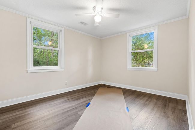 Spare room with healthy amount of natural light, wood finished floors, baseboards, a ceiling fan, and ornamental molding | Image 32
