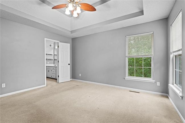 Unfurnished bedroom featuring carpet flooring, a raised ceiling, and multiple windows | Image 19