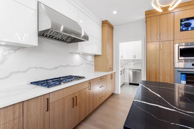 Kitchen featuring stainless steel appliances, wall chimney range hood, and modern cabinets | Image 11