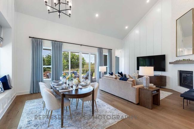 Dining space featuring high vaulted ceiling, wood finished floors, a chandelier, a large fireplace, and recessed lighting | Image 20