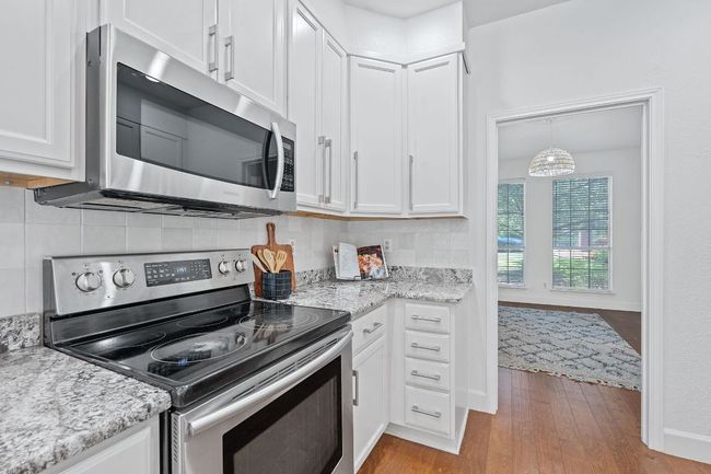 Kitchen featuring appliances with stainless steel finishes, white cabinets, and wood finished floors | Image 6