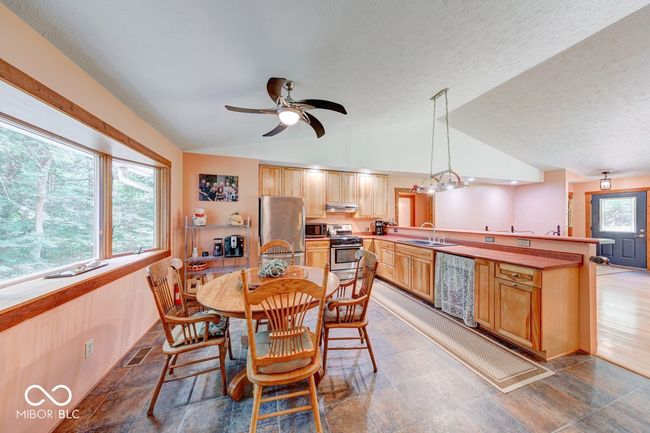 dining area featuring vaulted ceiling, a ceiling fan, and a textured ceiling | Image 45