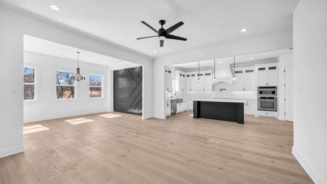 Unfurnished living room with light wood-style flooring, ceiling fan with notable chandelier, and baseboards | Image 11