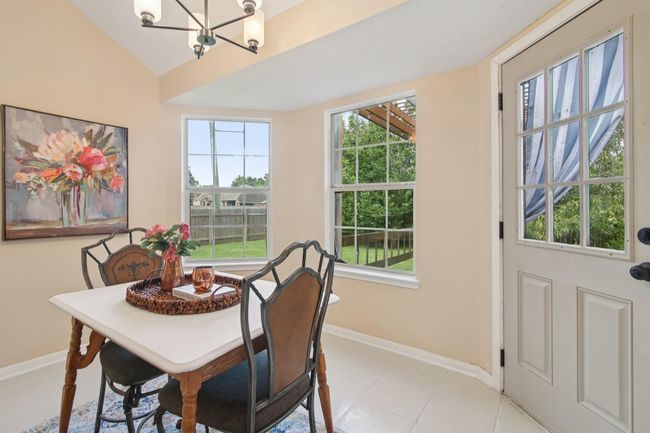 This cozy dining area features a bright, airy atmosphere with large windows overlooking a lush backyard. It is perfect for intimate meals or morning coffee. | Image 14