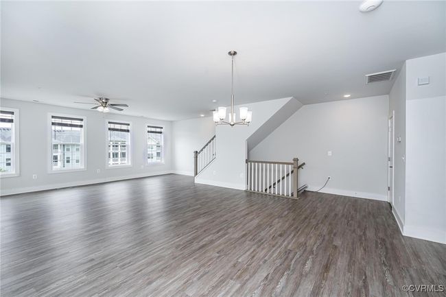 living room with wood finished floors, a ceiling fan, and a chandelier | Image 6