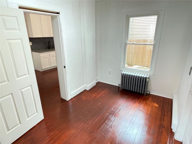 Empty room with radiator heating unit, dark wood-type flooring, and baseboards | Image 13
