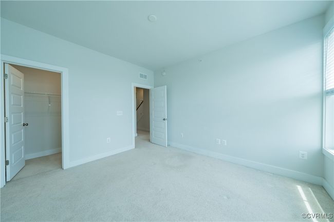 Unfurnished bedroom with light carpet, a walk in closet, baseboards, and a closet | Image 30