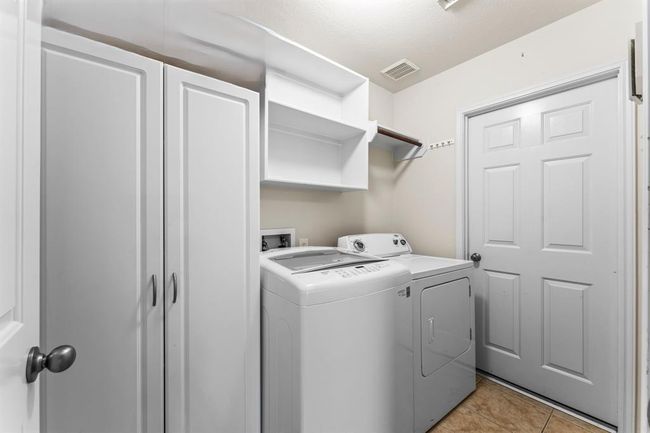 This well-organized laundry room features upper and lower cabinets for ample storage, plus open shelving and a hanging rod for convenience. | Image 14