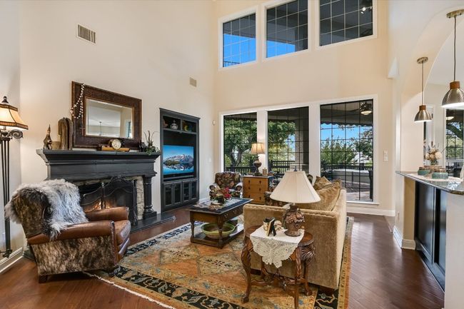 Living room with a stunning gas log fireplace, dark wood floors, and a towering ceiling | Image 8