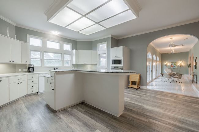 Kitchen with built in microwave, arched walkways, stainless steel oven, light wood finished floors, and crown molding | Image 13