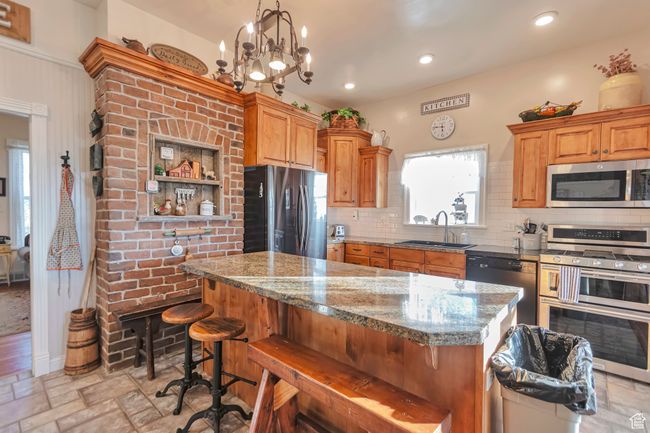 Kitchen featuring light stone countertops, a center island, stainless steel appliances, an inviting chandelier, and sink | Image 33