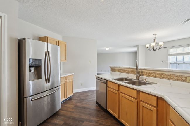 kitchen with appliances with stainless steel finishes, a sink, a chandelier, light countertops, and a textured ceiling | Image 29