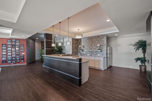 Kitchen with a tray ceiling, hanging light fixtures, freestanding refrigerator, light stone countertops, and recessed lighting | Image 51