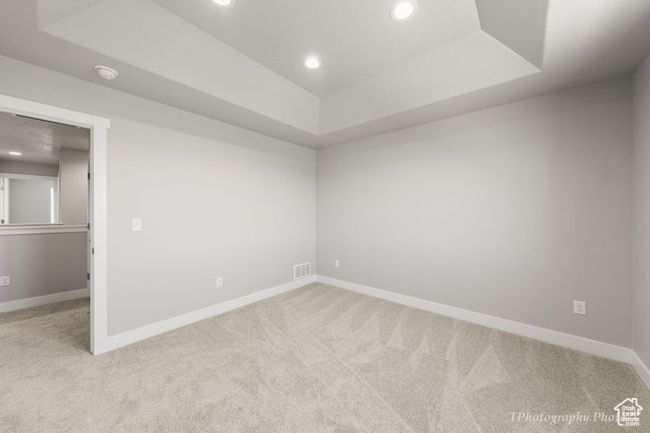Carpeted empty room featuring a tray ceiling, recessed lighting, baseboards, and a smoke detector | Image 14