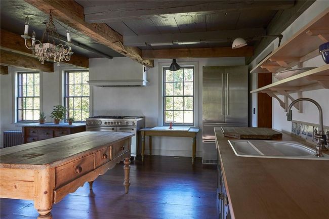 Kitchen featuring dark wood-type flooring, custom range hood, radiator heating unit, and high quality appliances | Image 11